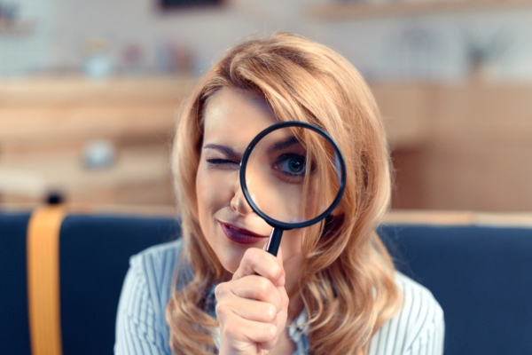 woman looking through a magnifying glass depicting how asbestos insulation looks like