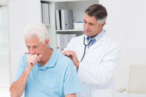 doctor listening to a man's lungs depicting health hazards of insulation removal