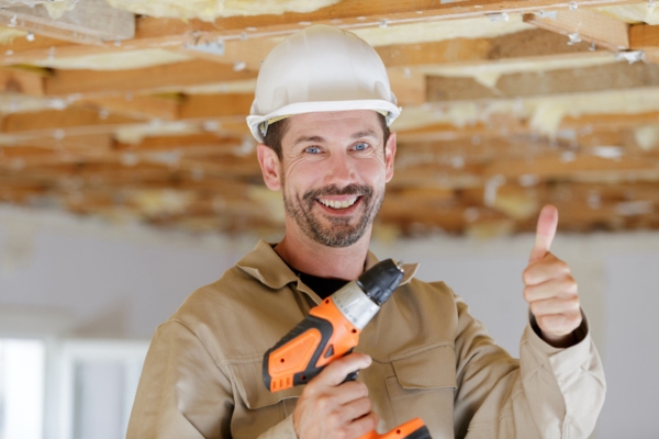 image of a professional insulation contractor holding a tool on one hand and doing a thumbs up on another hand