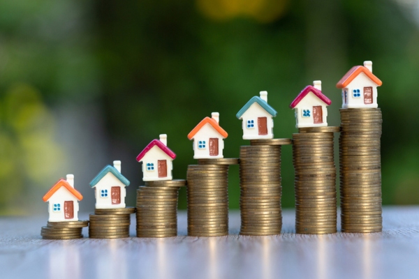 Miniature Houses on a pile of coins creating coin ladder depicting increase in property value