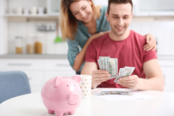 image of a piggy bank and blurred couple counting money depicting savings from insulation