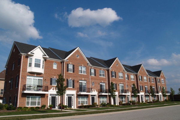 A row of brick townhouses under a blue sky