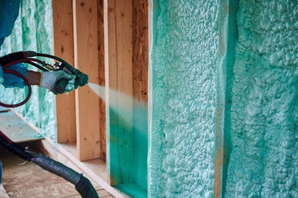 Builder insulating wooden frame house using spray foam depicting insulation installation