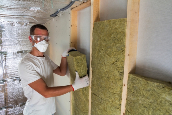 Worker installing rock wool insulation on main floor of the house